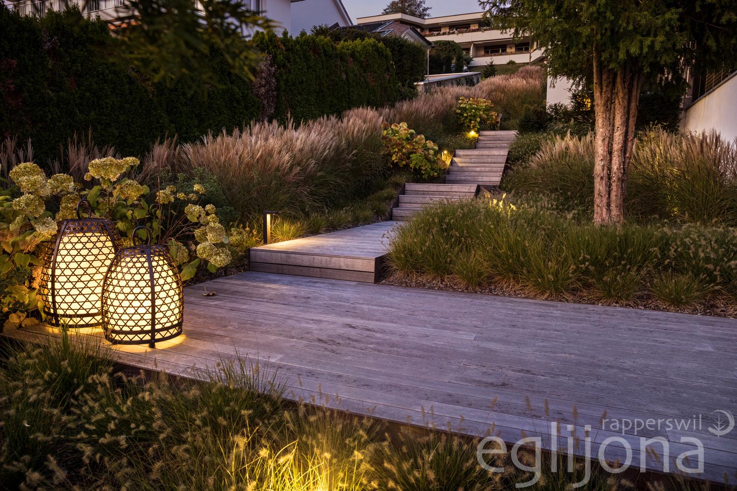 Die Gartengestaltung besticht durch die luftige Bepflanzung, den Pool und die abendliche Beleuchtung.